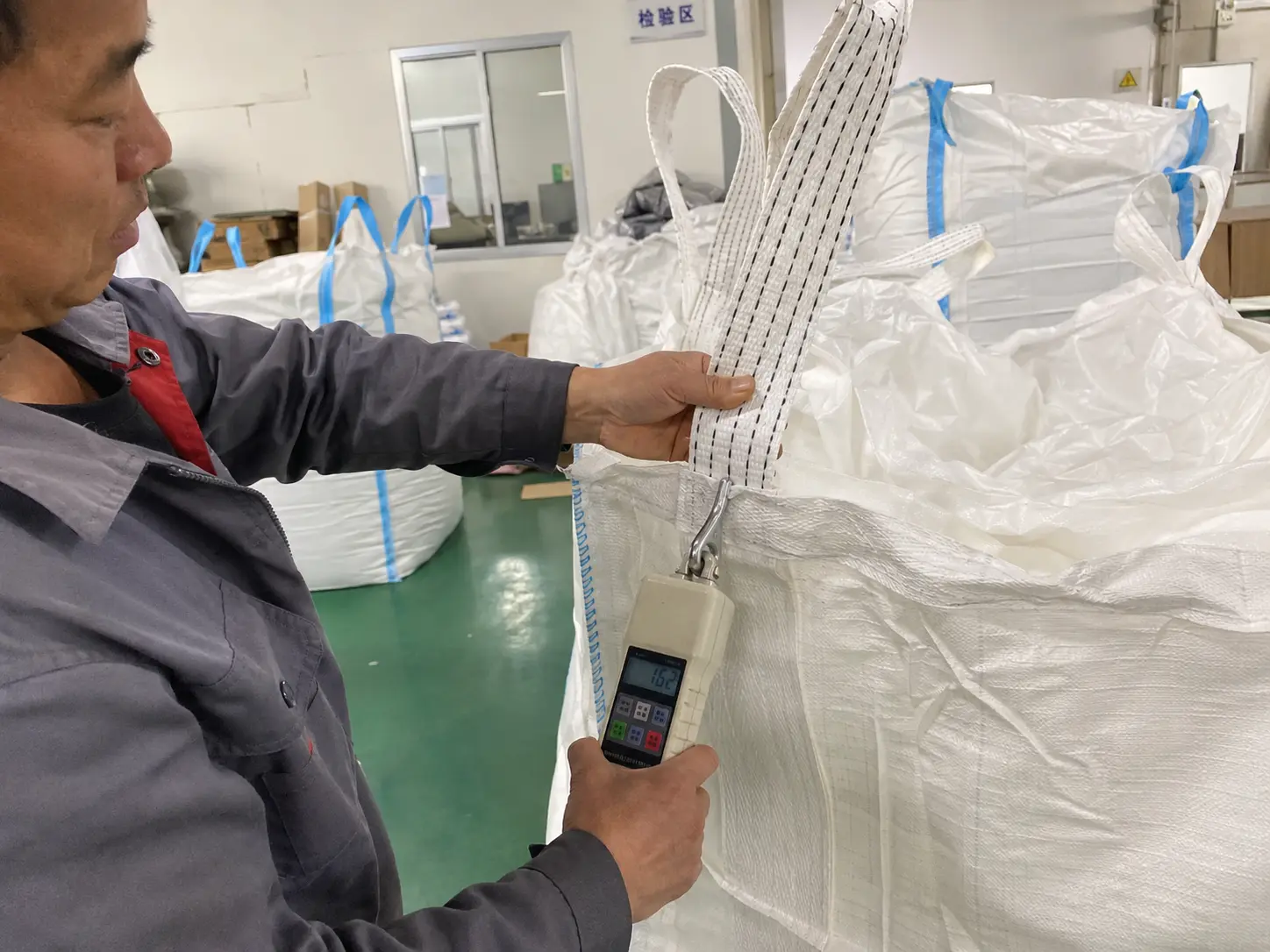Quality control technician performing a pull test on FIBC bulk bag lifting loops at a partner factory